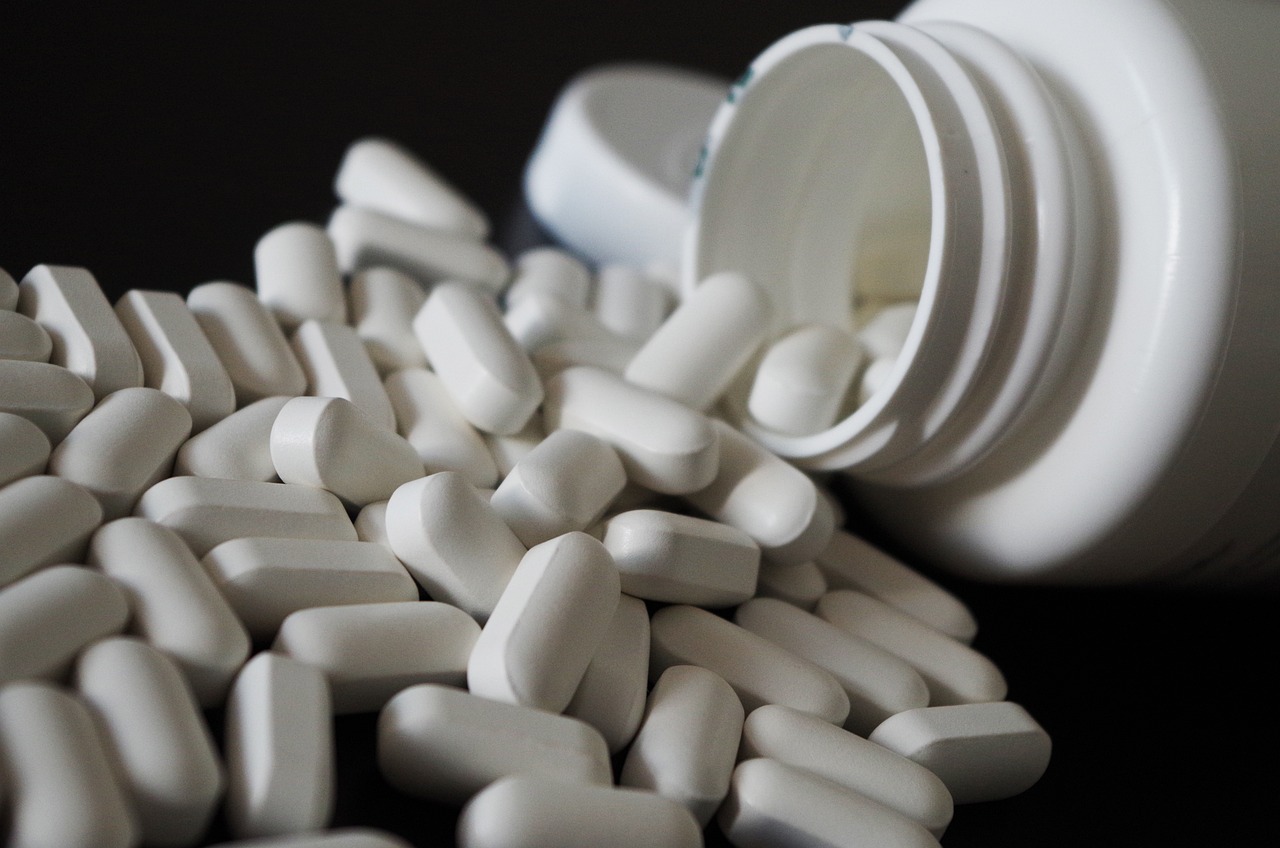 a pile of white pills spilling out of a bottle, pixabay, plasticien, stock photo, shoulder, hibernation capsule close-up, against dark background