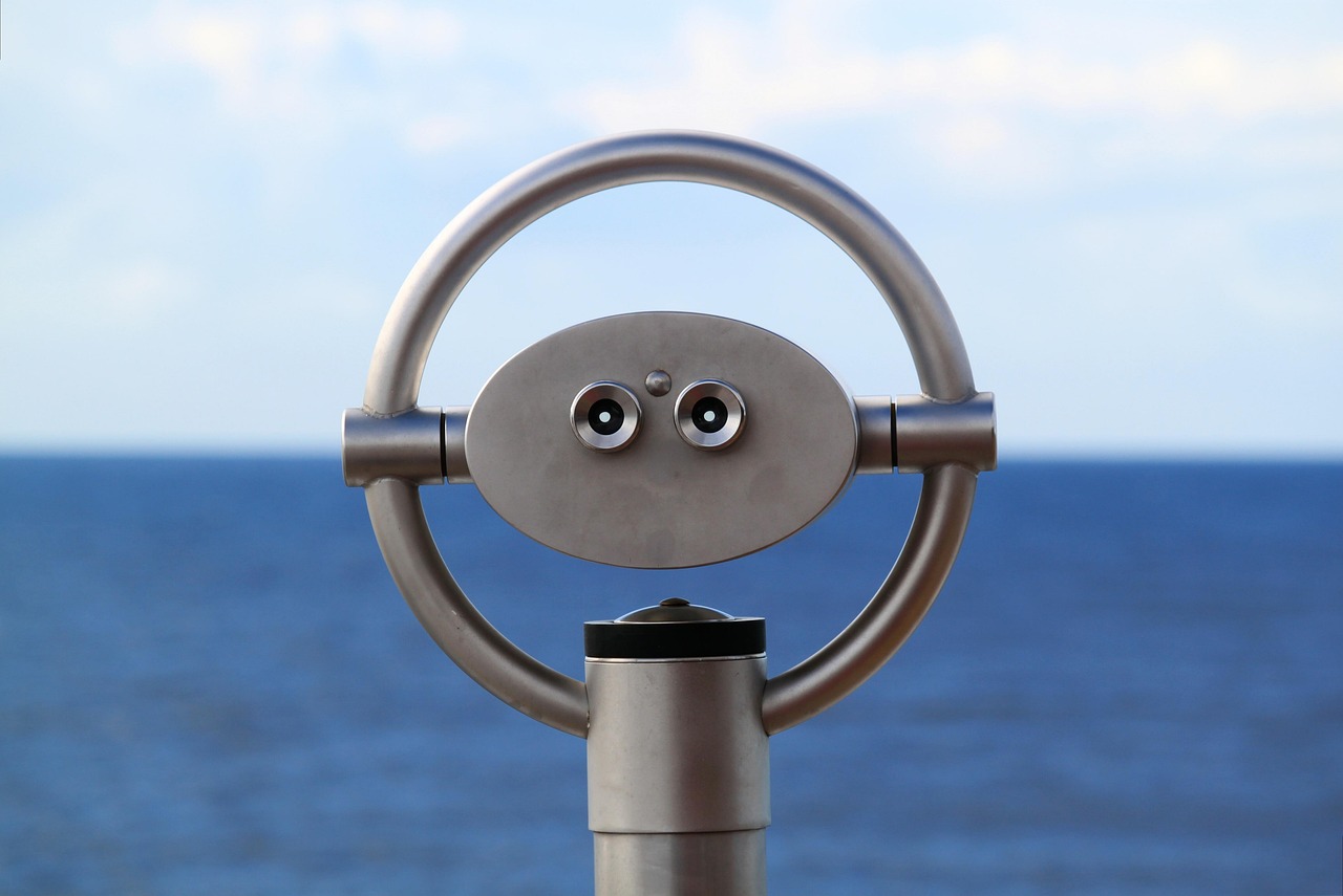 a close up of a coin operated telescope with the ocean in the background, inspired by Rene Magritte, kinetic art, with symmetrical head and eyes, very cute robot zen, security camera photo, metal sculpture
