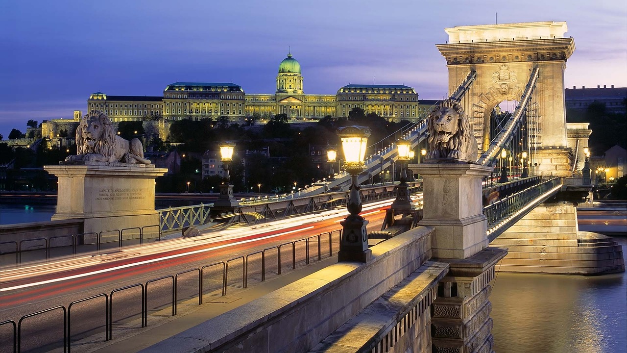 a bridge over a river with a building in the background, by László Balogh, shutterstock, fine art, royal palace, city lighting, sweeping vista, bridges and railings