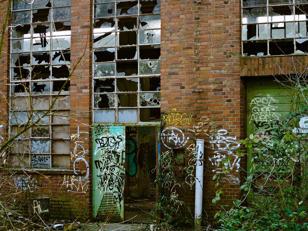 a building with broken windows and graffiti all over it, by Richard Carline, flickr, graffiti, 2 5 mm portra, factories and nature, elstree, many doorways