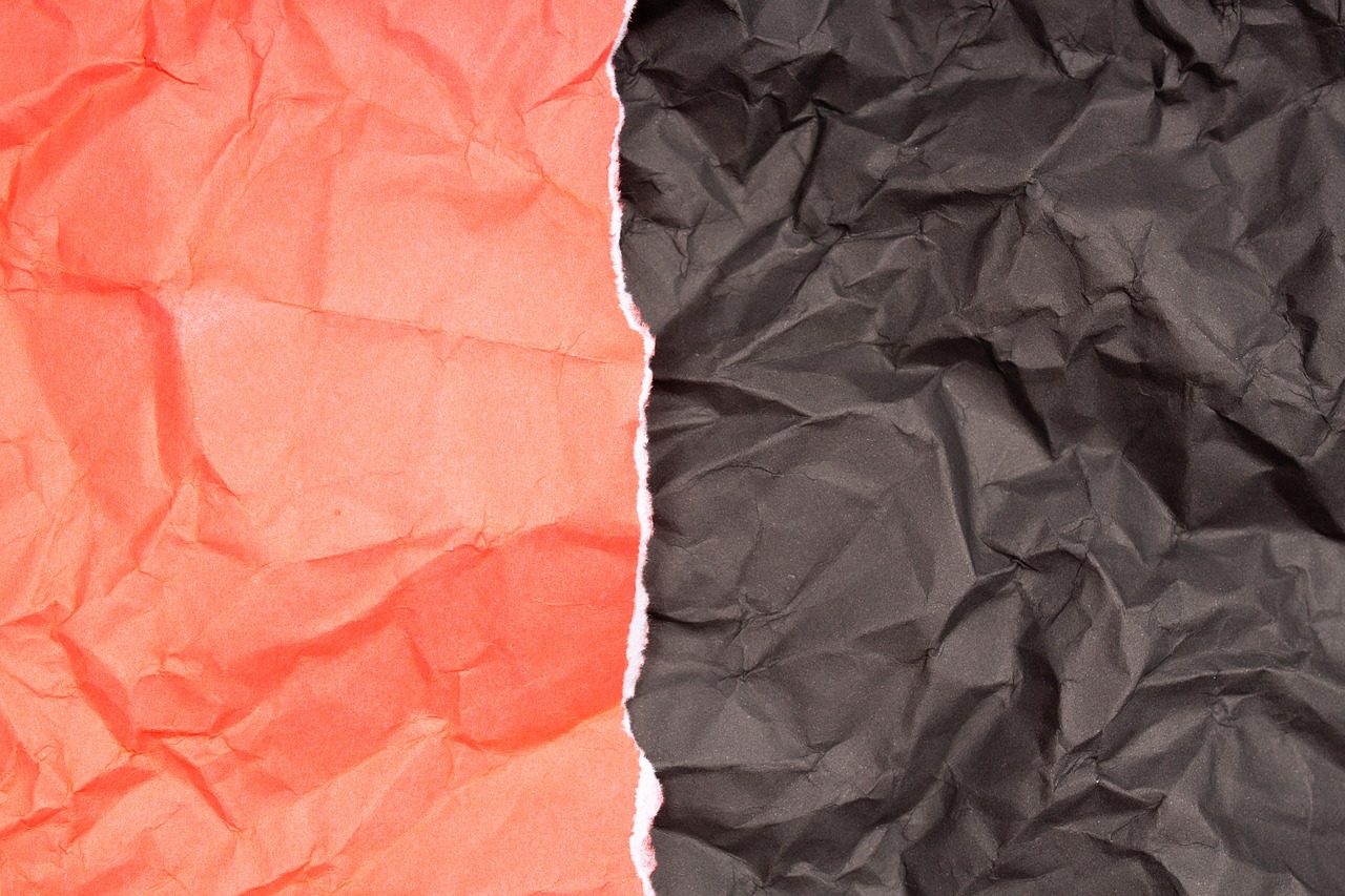 two pieces of red and black crumpled paper, a photo, closeup photo, very accurate photo