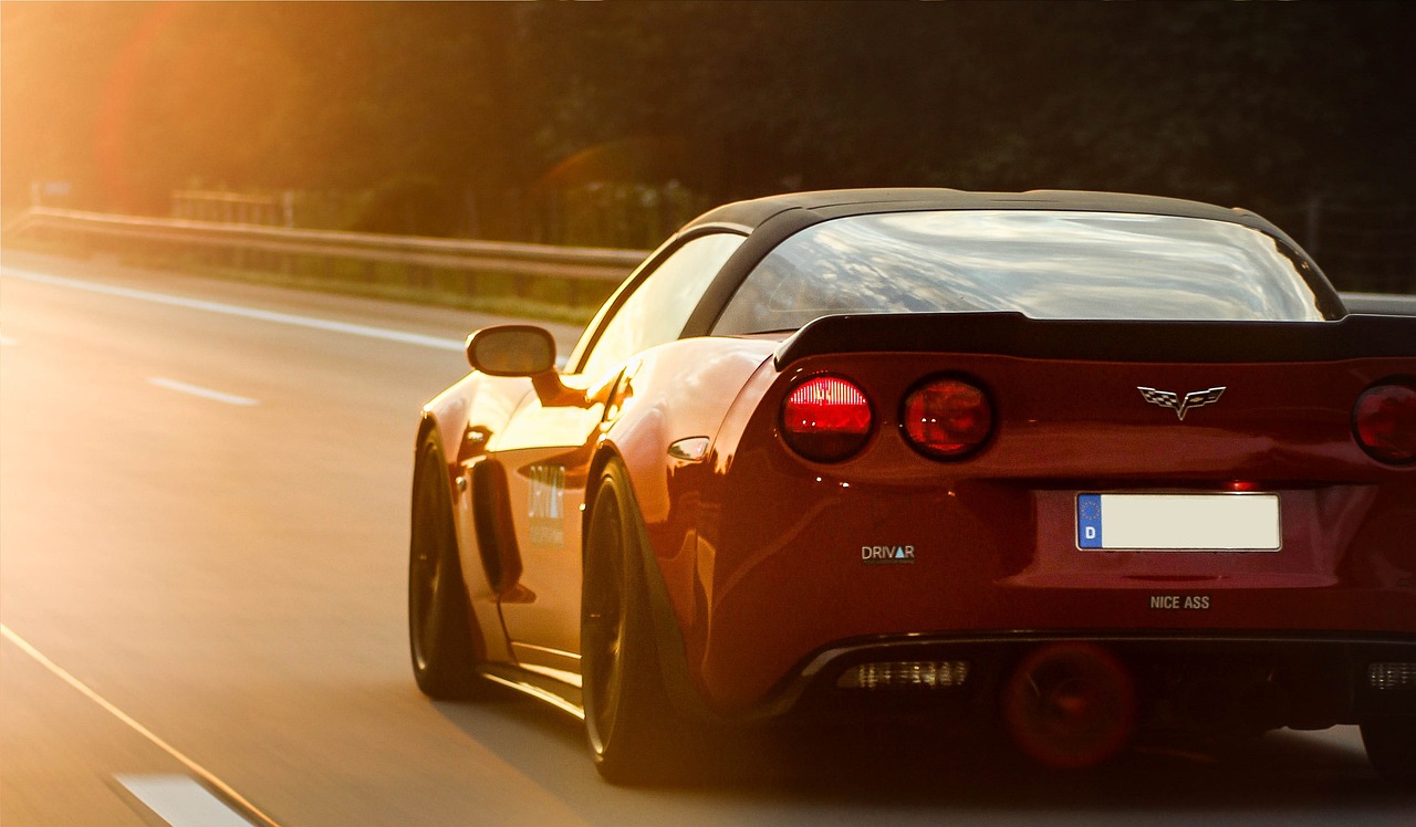 a red sports car driving down a highway, a picture, tumblr, romanticism, corvette c2 1969, back light, ultra wide, race car