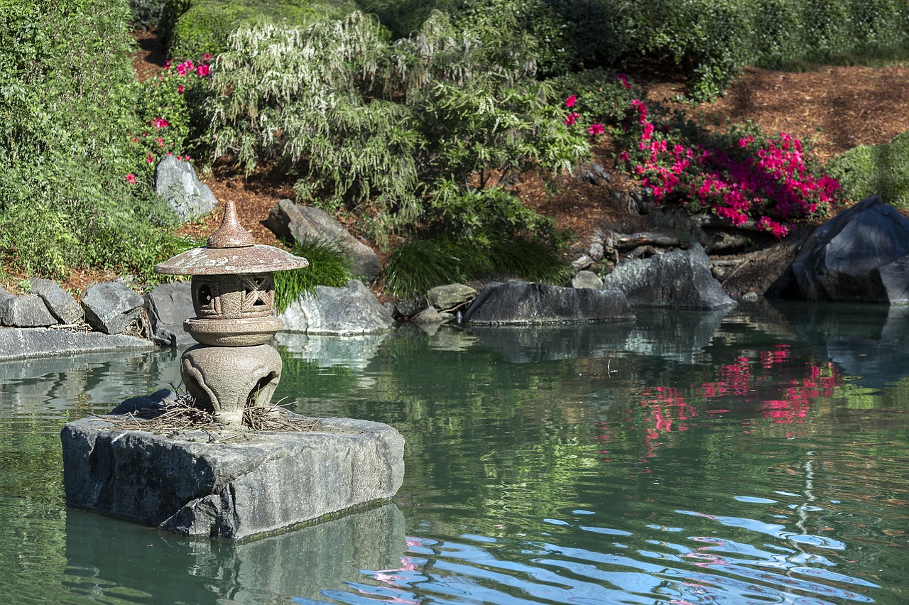 a stone lantern sitting on top of a rock in a pond, a picture, inspired by Tōshi Yoshida, shutterstock, draped with red hybiscus, 2 4 mm iso 8 0 0 color, sculpture gardens, water reflection!!!!!