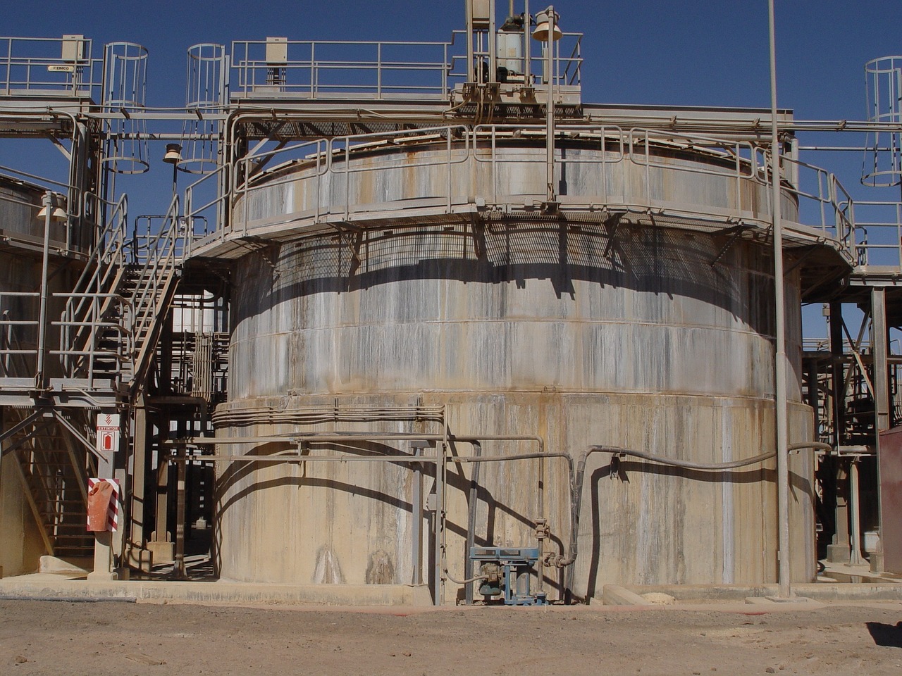 a large metal tank sitting on top of a dirt field, a picture, flickr, industrial rusty pipes, oman, high technology inplants, acid pooling inside