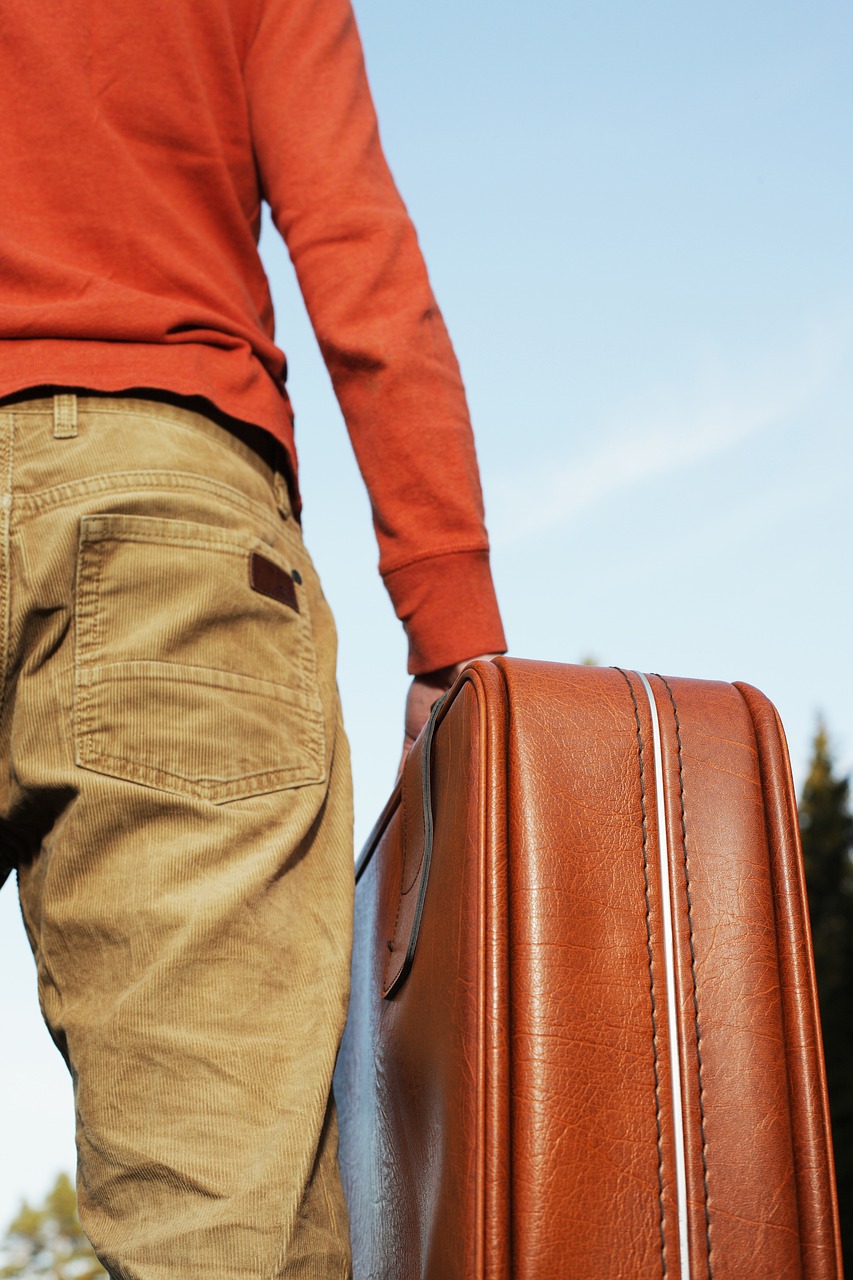 a close up of a person holding a piece of luggage, a picture, by Kurt Roesch, shutterstock, brown pants, on a sunny day, stock photo, powerful detail