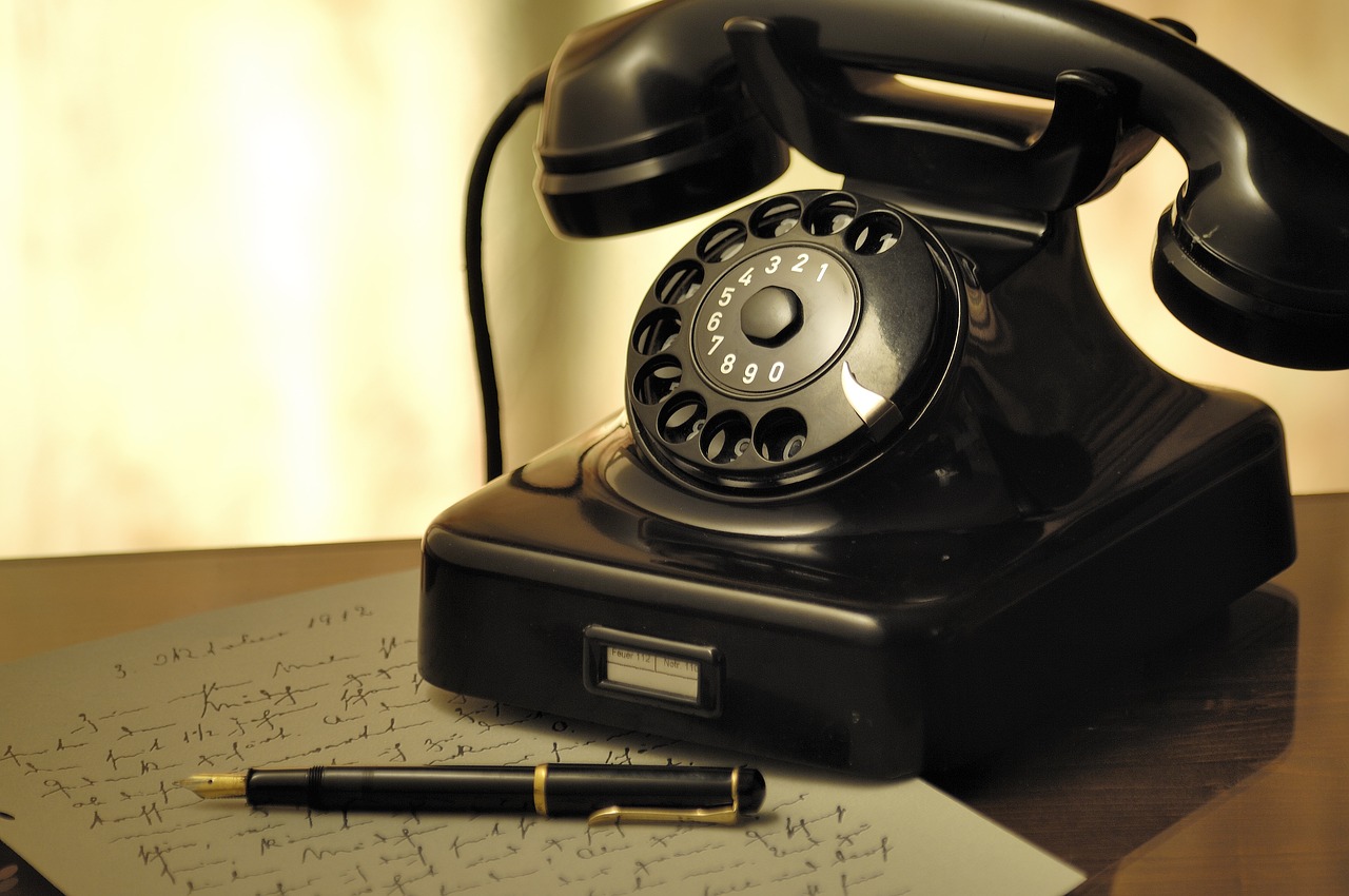 a telephone sitting on top of a desk next to a pen, a photo, by Aleksander Gierymski, dial, retro technology, have a call to action, very very realistic