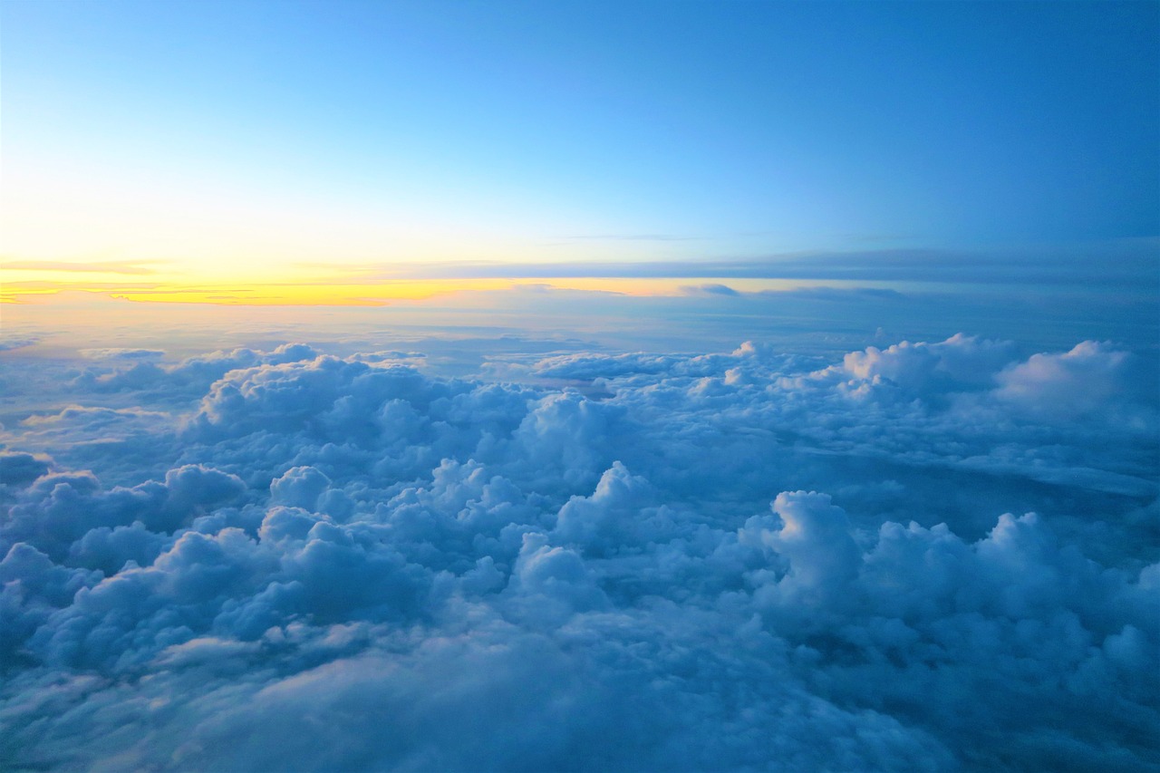 a view of the sky and clouds from an airplane, shutterstock, beautiful sunrise, blue - yellow sky, loots of clouds, over the ocean