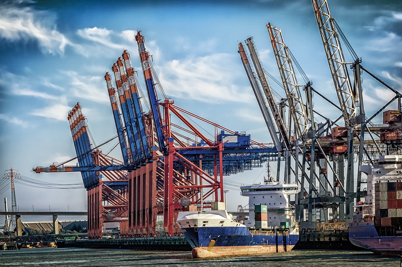 a couple of boats that are sitting in the water, a tilt shift photo, by Werner Gutzeit, modernism, huge machine cranes, hdr photo, megastructure in the background, shipping containers