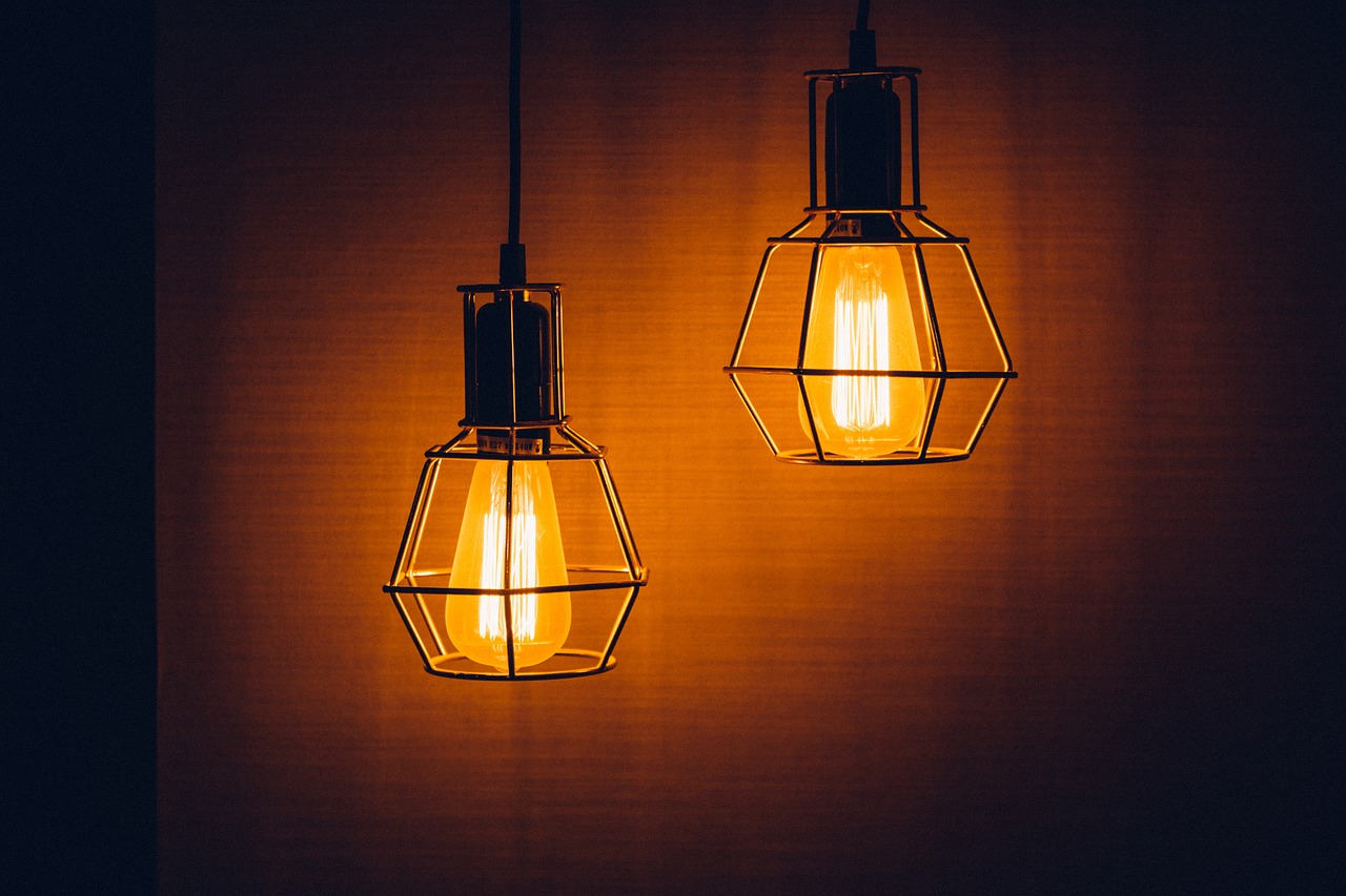 a couple of lights that are on a wall, pexels, light and space, orange electricity, award winning dark lighting, istock, hanging lanterns