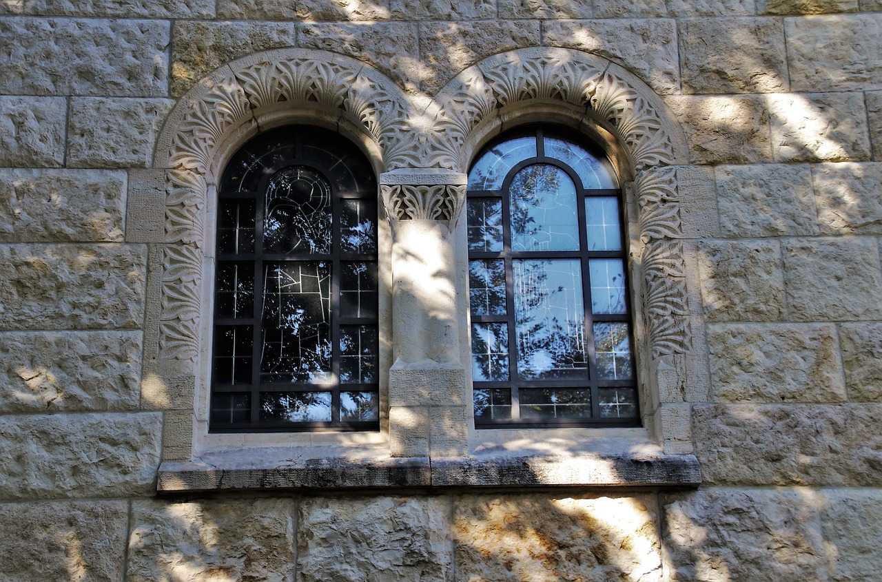 a couple of windows sitting on top of a stone building, a mosaic, by Leo Michelson, flickr, romanesque, detailed carved ornaments, the narthex, built into trees and stone, orthodox mosaic