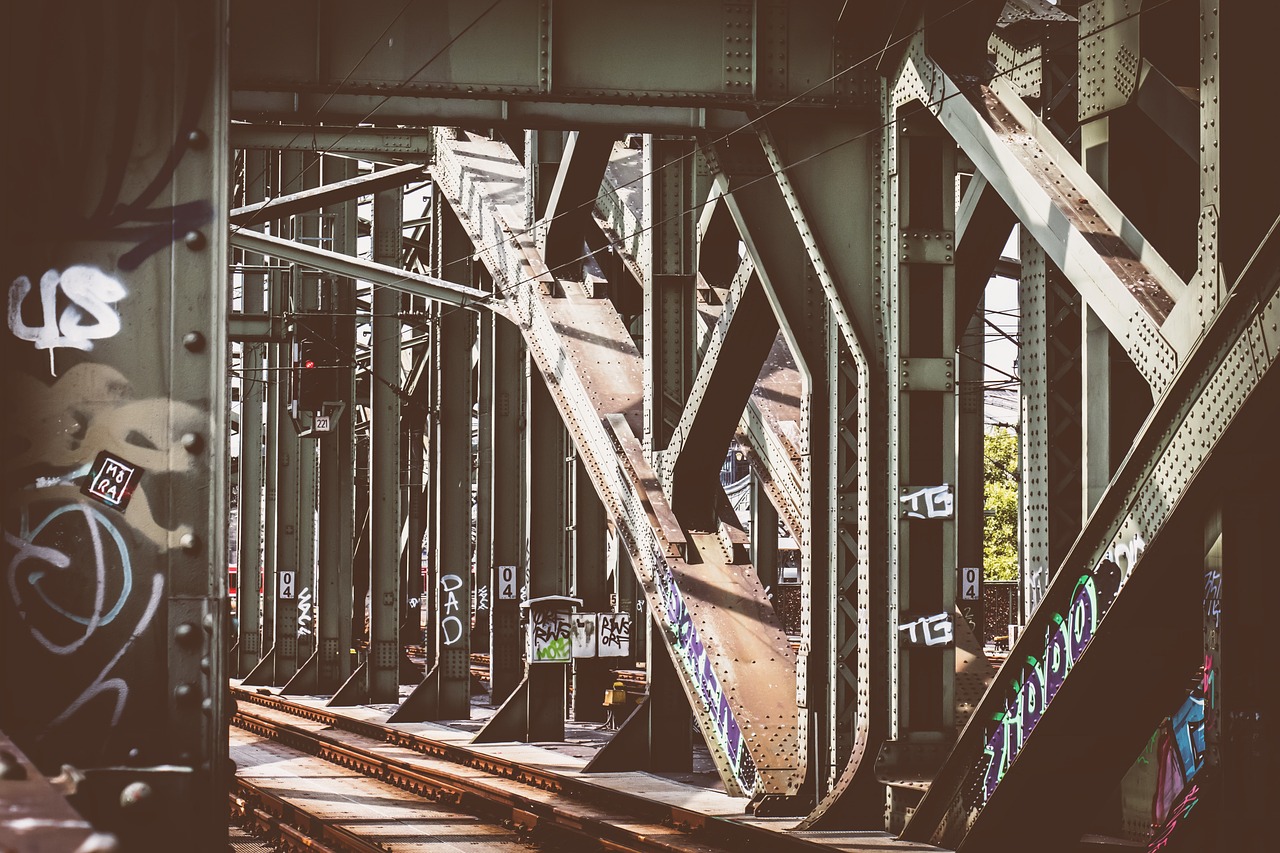 a train traveling through a train station covered in graffiti, unsplash, suspended bridge!, bridges crossing the gap, matte detailed photo, intense sunlight