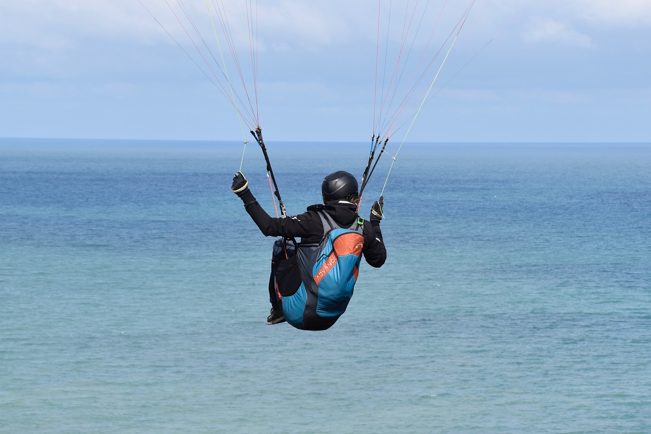 a man flying through the air while riding a kiteboard, a picture, by Robert Brackman, shutterstock, wearing a flying jacket, parachutes, looking towards the horizon, back