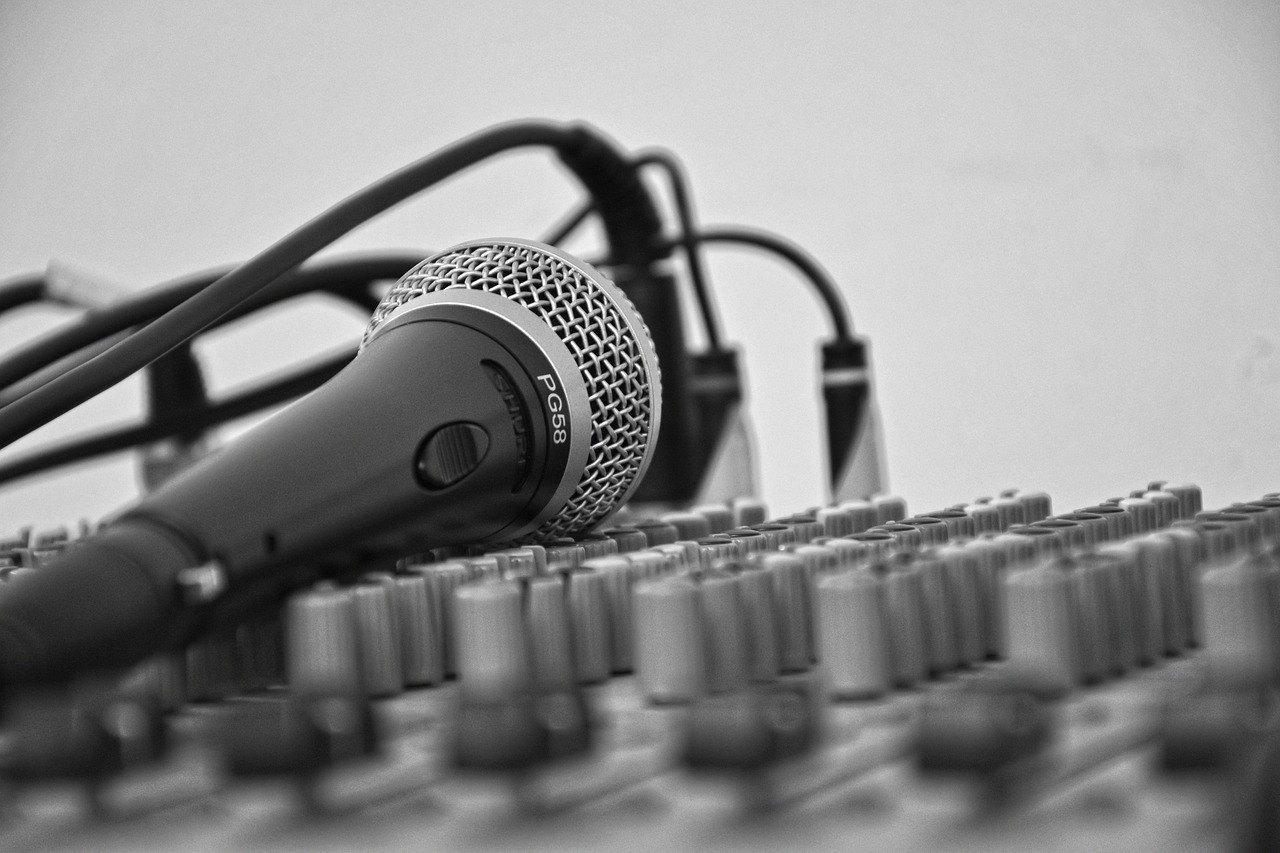 a microphone sitting on top of a sound board, by Mirko Rački, pexels, digital art, cables out of the ears, monochromatic photo, dialogue, with head phones