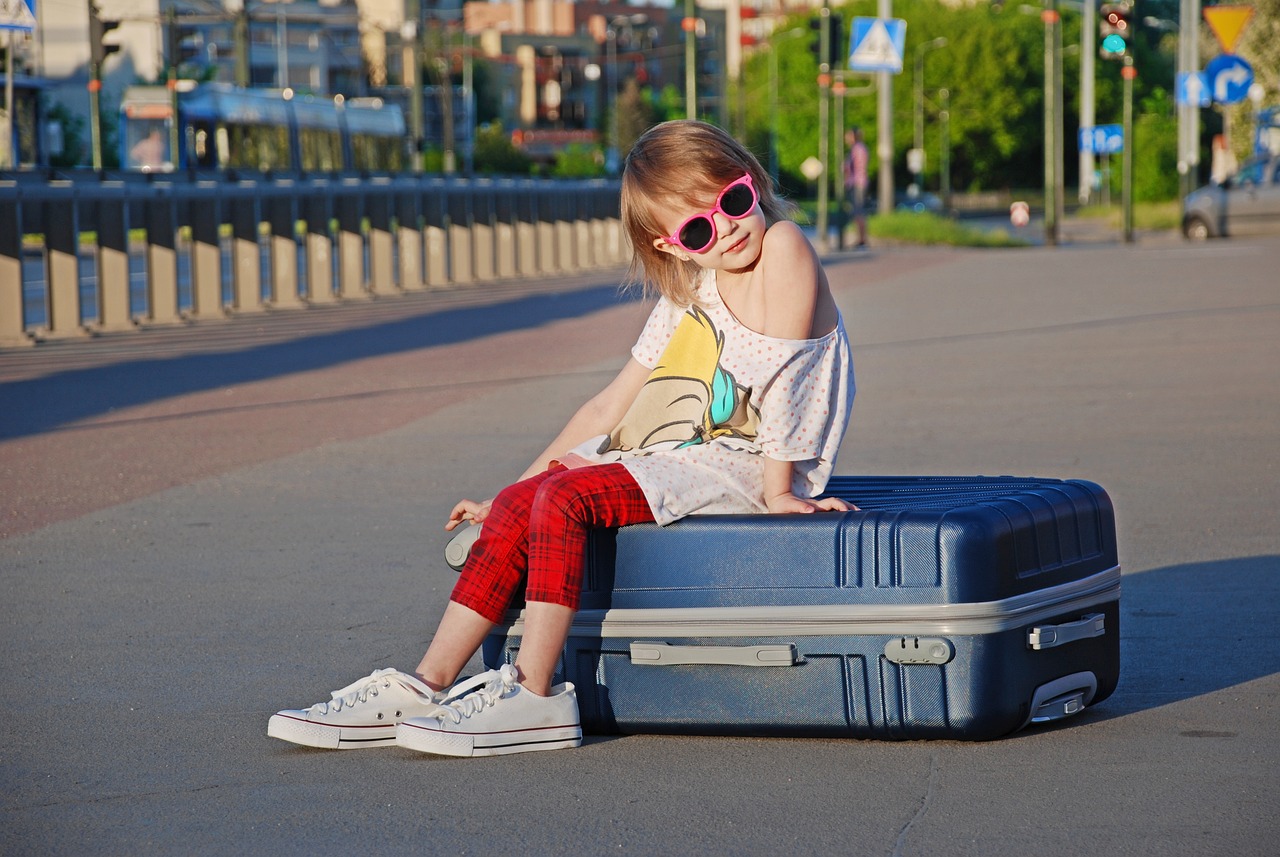 a little girl sitting on top of a suitcase, a picture, shutterstock, stock photo, sunny day, cool marketing photo, trending photo