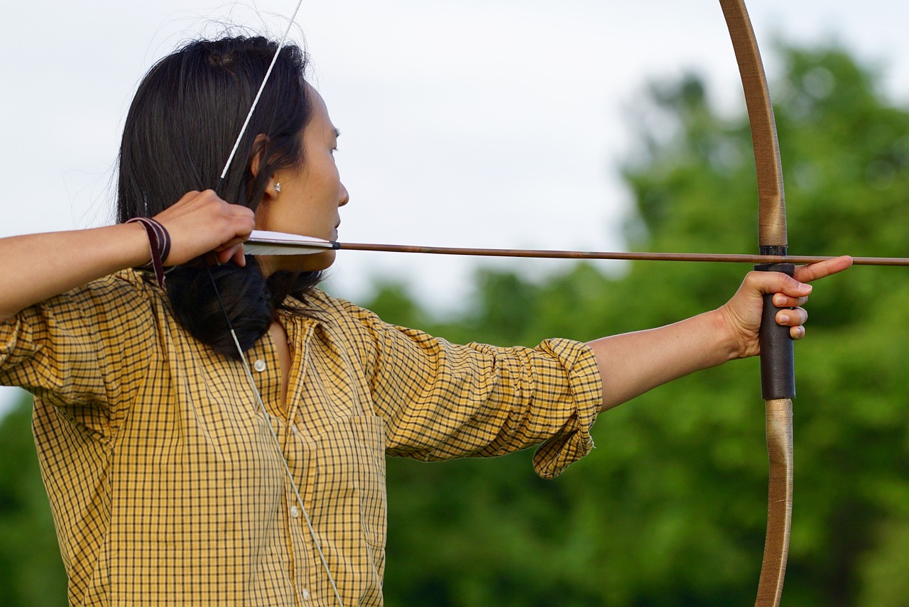 a woman that is holding a bow and arrow, zoom shot, panoramic shot, on the bow, cindy avelino