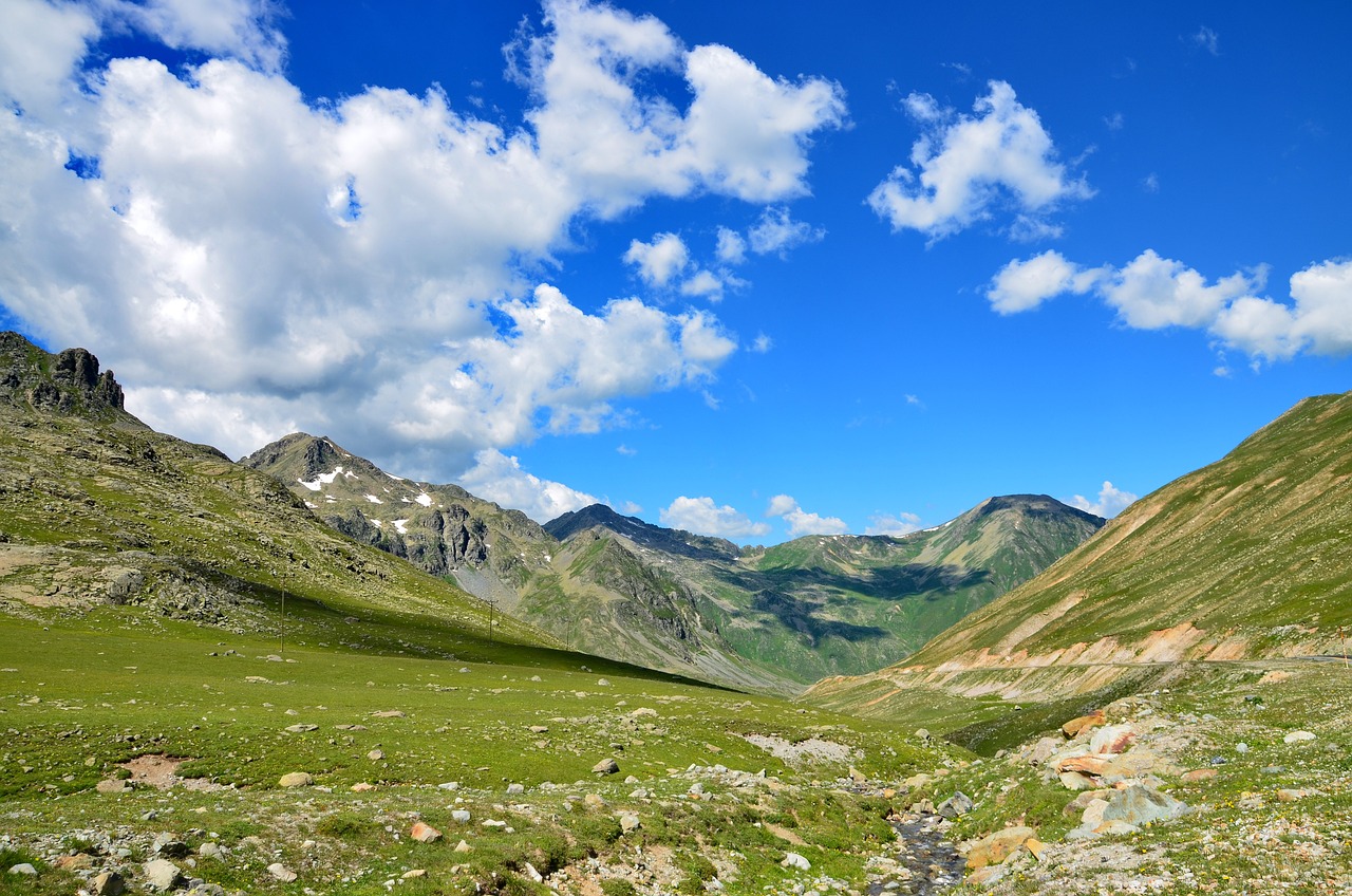 a person riding a horse through a lush green valley, by Werner Andermatt, shutterstock, les nabis, summer landscape with mountain, wide angle shot 4 k hdr, rocky meadows, blue sky with colorful clouds