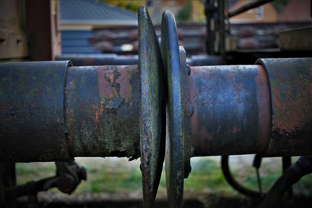 a close up of a rusty pipe with a building in the background, by Thomas Häfner, flickr, truck, grungy; colorful, cart wheels, detailed abstract