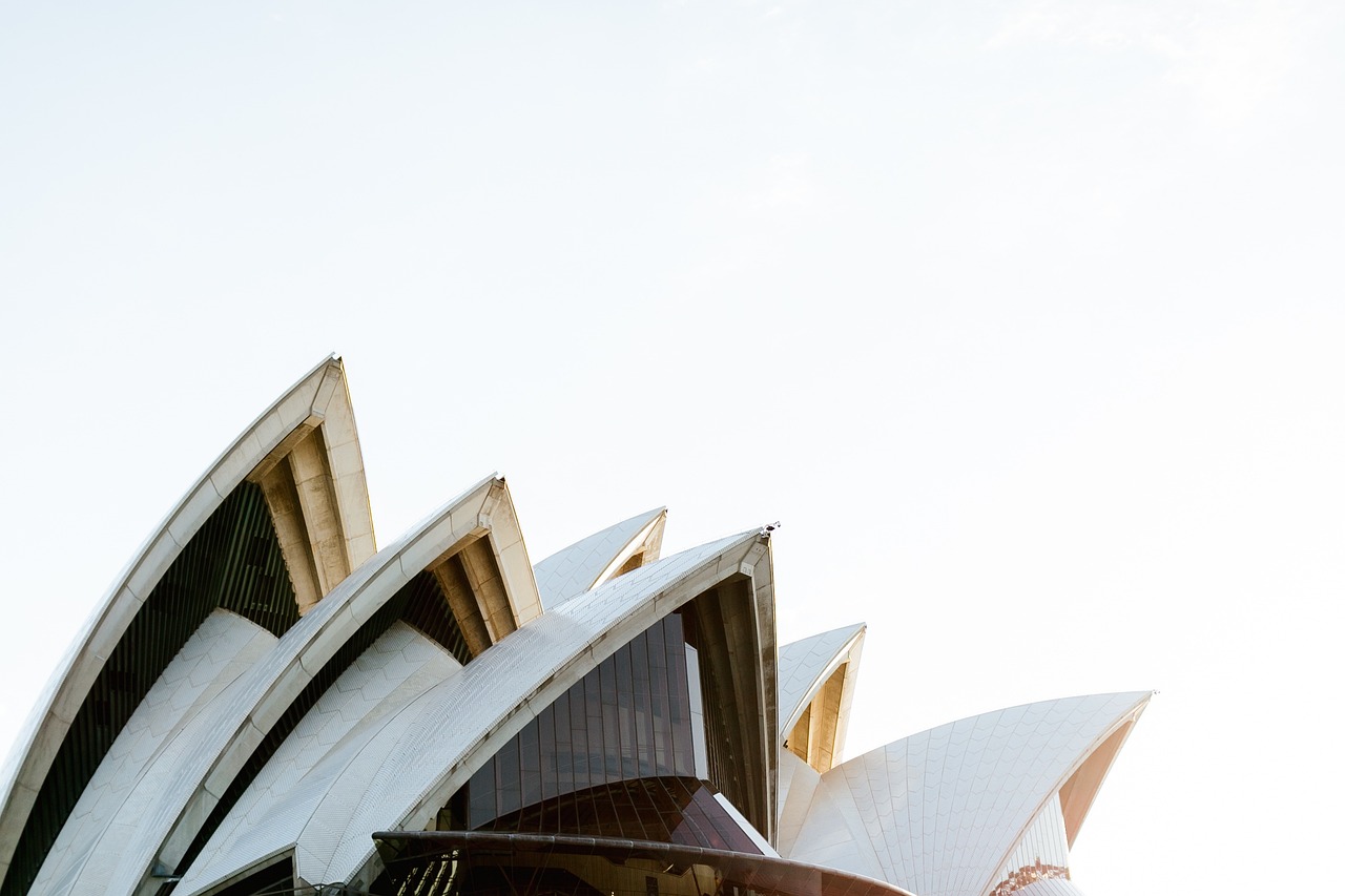 a view of the sydney opera house from below, a tilt shift photo, white minimalist architecture, shot at golden hour, conde nast traveler photo