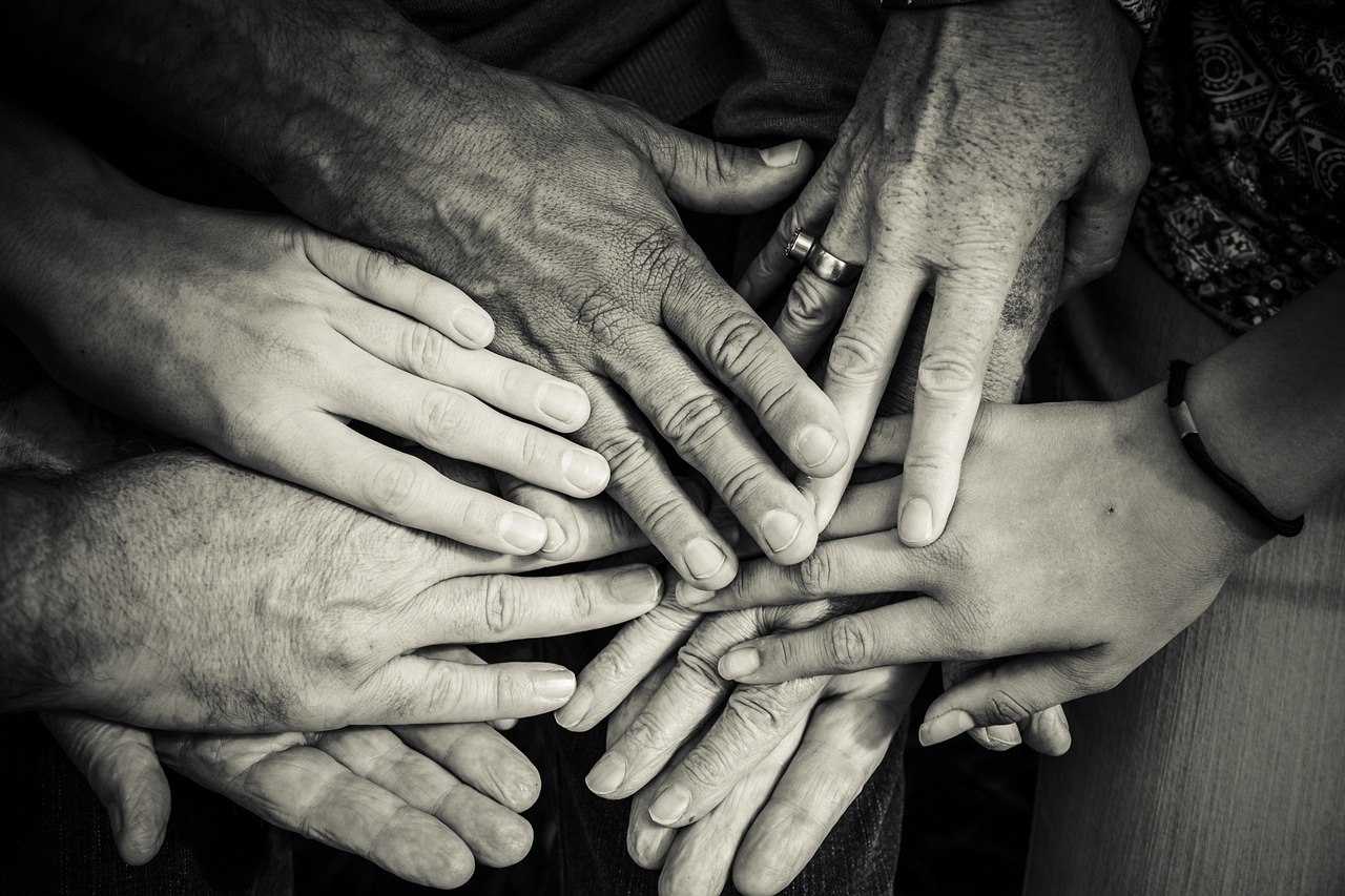 a group of people putting their hands together, a black and white photo, by Mirko Rački, flickr, renaissance, professionally post-processed, soft texture, family, ! low contrast!