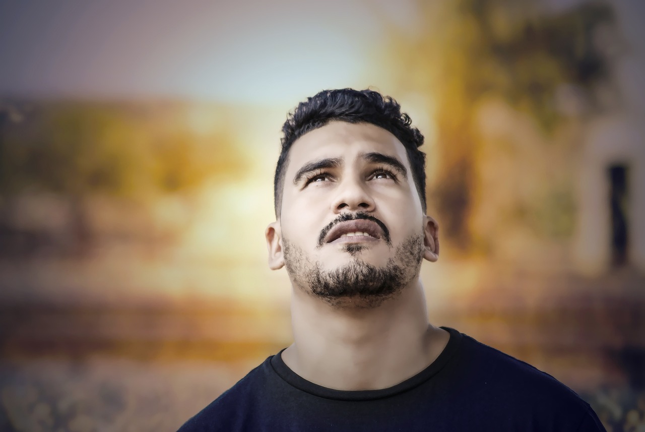 a man in a black shirt looking up at the sky, a character portrait, shutterstock, realism, mexican mustache, shot at golden hour, tired and haunted expression, face photo