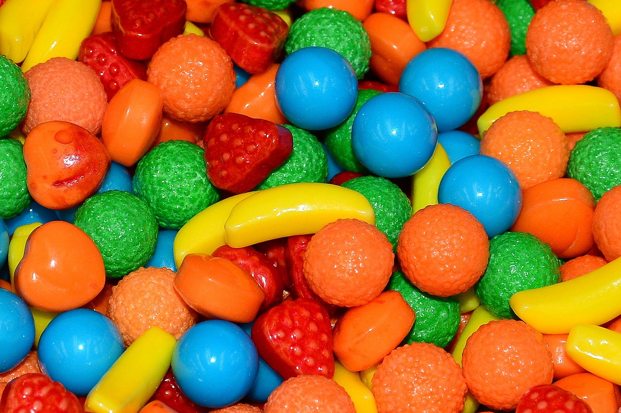 a pile of colorful candy sitting on top of a table, by Arnie Swekel, strawberry granules, space jammers, orange, mid closeup