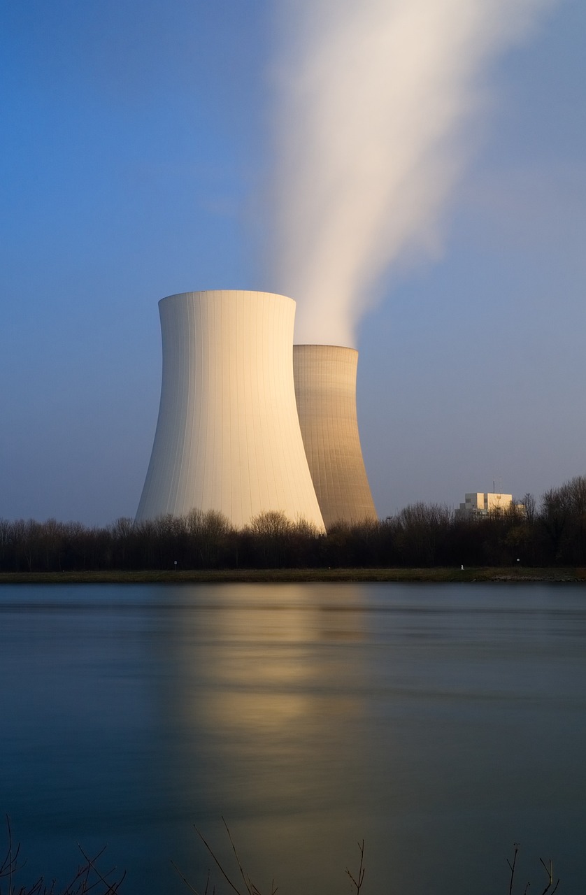 a couple of cooling towers next to a body of water, a picture, by Etienne Delessert, shutterstock, nuclear art, wayne barlowe pierre pellegrini, wikimedia commons, waist - shot, atom