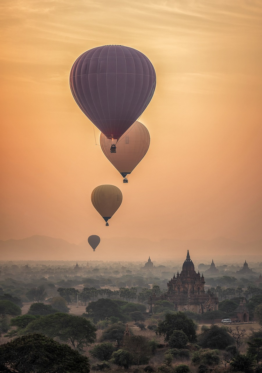 a couple of hot air balloons flying in the sky, a picture, by Artur Tarnowski, myanmar, in soft dreamy light at sunset, ancient city landscape, the photo was taken from afar
