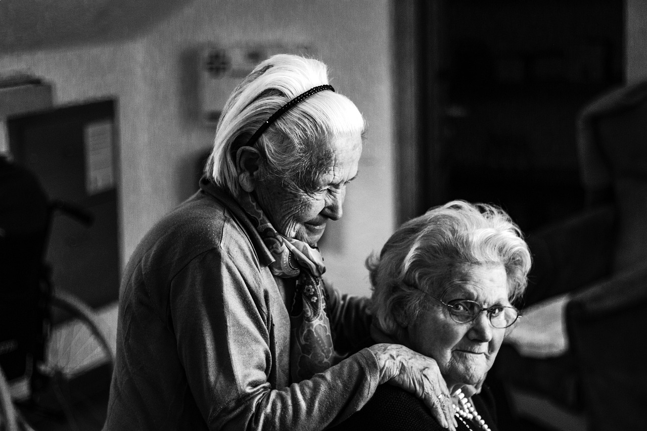 a black and white photo of two older women, by Matija Jama, pexels, head turned, at home, trending photo, hug