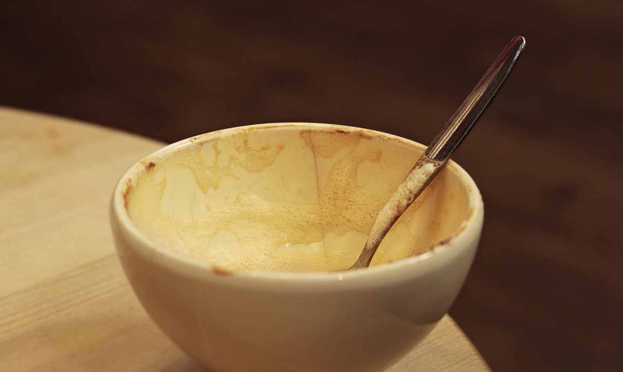 a close up of a bowl with a spoon in it, flickr, coffee stain, completely empty, cheesy, made of glazed