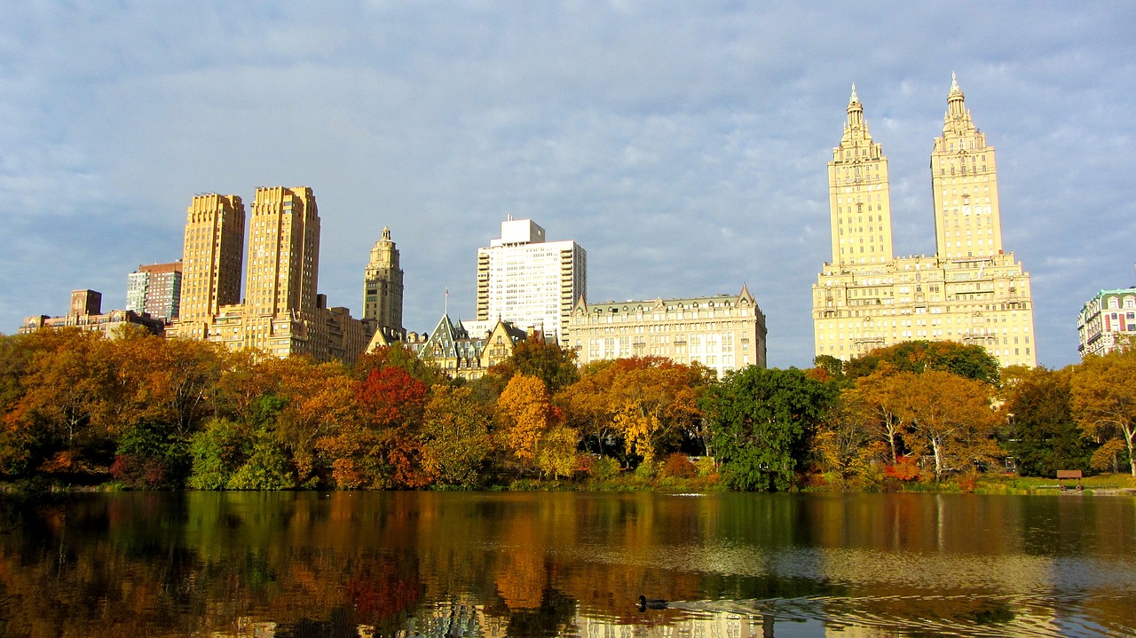 a large body of water surrounded by tall buildings, flickr, art nouveau, fall foliage, calvin klein, wikimedia, new york buildings