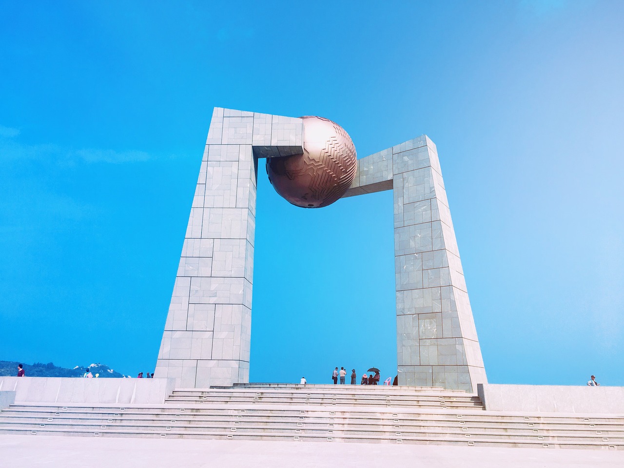 a group of people standing in front of a monument, an abstract sculpture, by Simon Gaon, pexels contest winner, new sculpture, portal to outer space, guangjian, seaview, blocking the sun