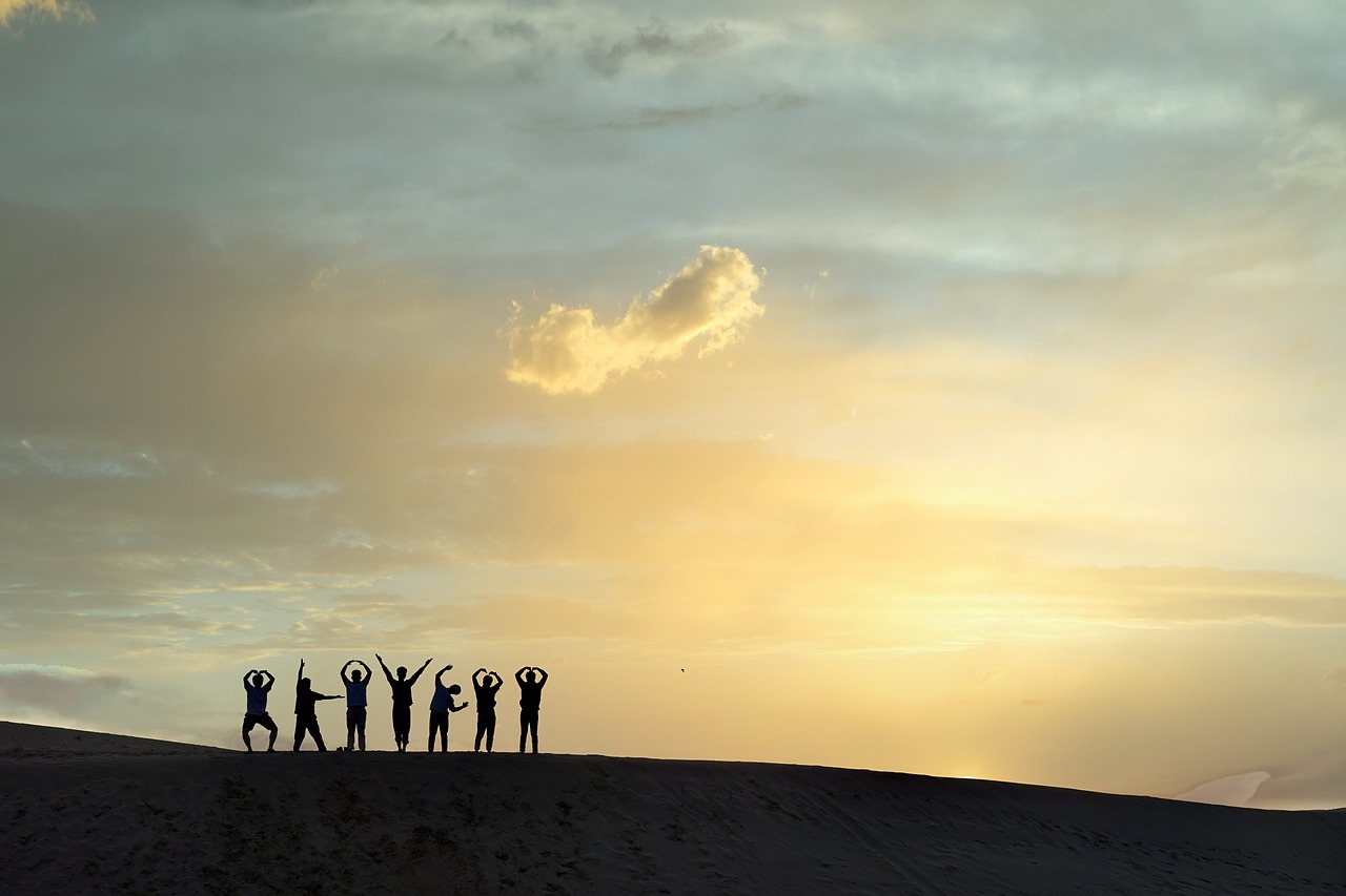 a group of people standing on top of a sand dune, a picture, by Han Gan, praising the sun, yoga, sun down, taken with canon 8 0 d