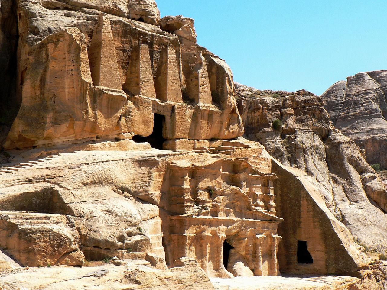 a group of people standing in front of a cave, pexels, hurufiyya, buildings carved out of stone, closeup - view, boe jiden, wikimedia