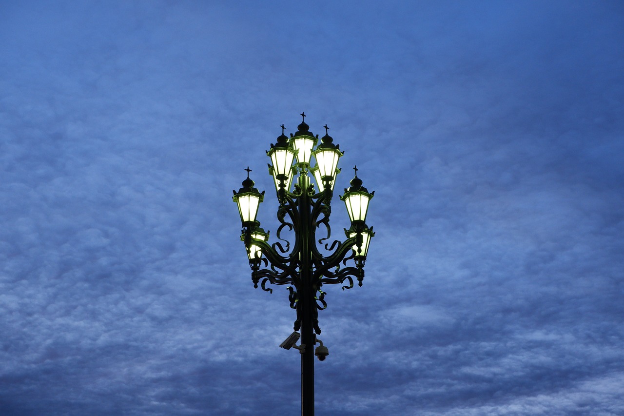 a street light with a cloudy sky in the background, a photo, by Andrei Kolkoutine, shutterstock, baroque, set at night, exquisitely ornate, multiple lights, famous designer lamp