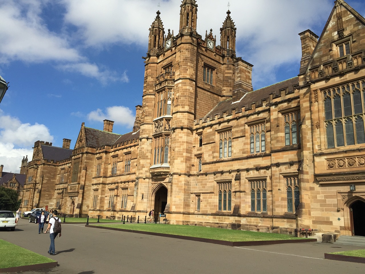 a group of people walking in front of a large building, inspired by Sydney Prior Hall, shutterstock, academic art, magic uniform university, wide angle establishing shot, shot on iphone 6, tudor architecture