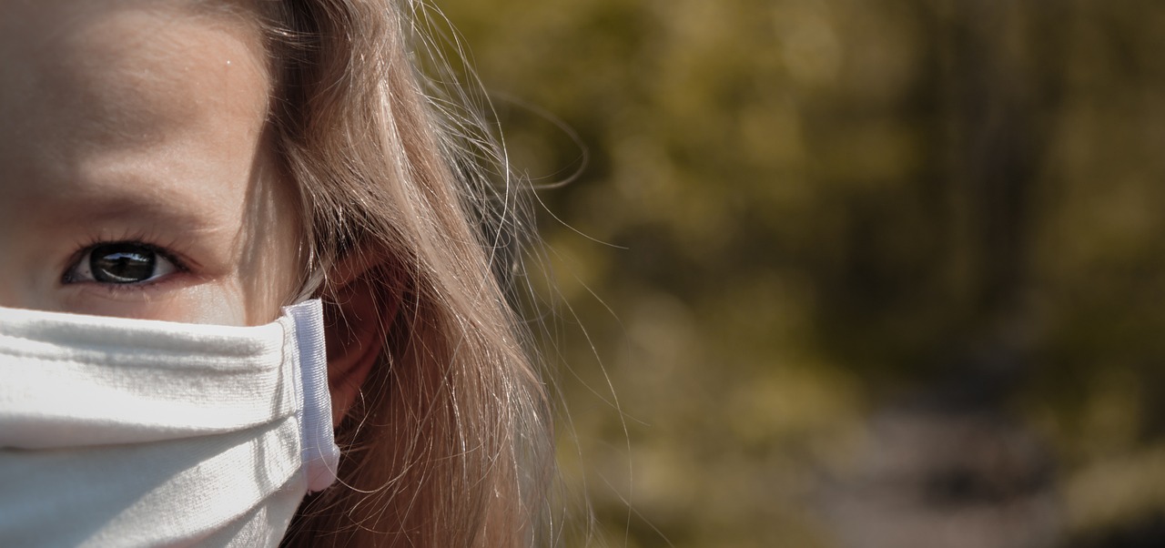 a close up of a child wearing a face mask, a picture, by Richard Carline, trending on pixabay, photorealism, blonde hair with a pony tail, in the sun, an earring, banner