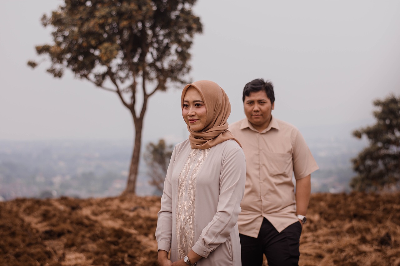 a man and a woman standing next to each other, a picture, tumblr, sumatraism, background image, standing on a hill, side portrait imagery, wife