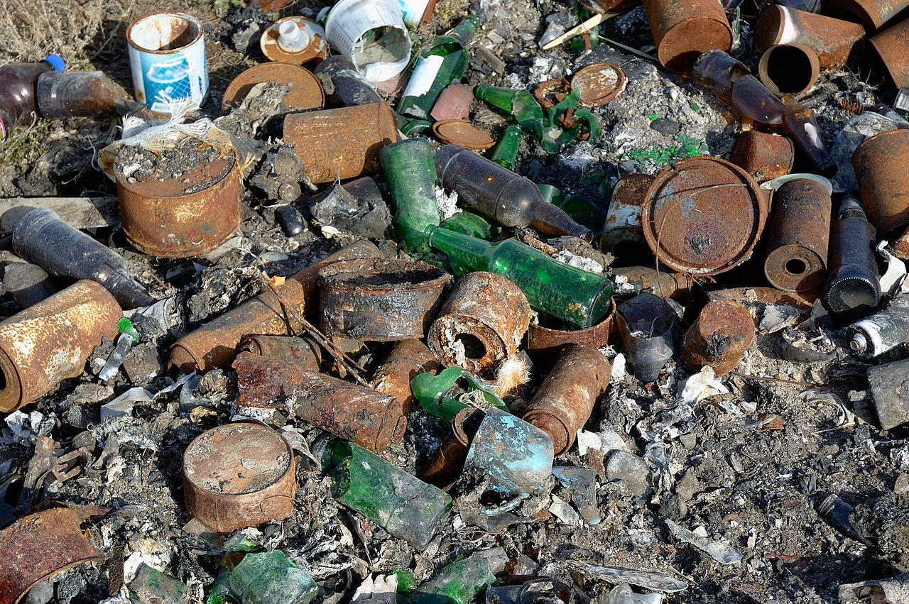 a pile of bottles sitting on top of a pile of dirt, by Brenda Chamberlain, flickr, plasticien, abandoned steelworks, close up camera on bonfire level, emerald, closeup!!