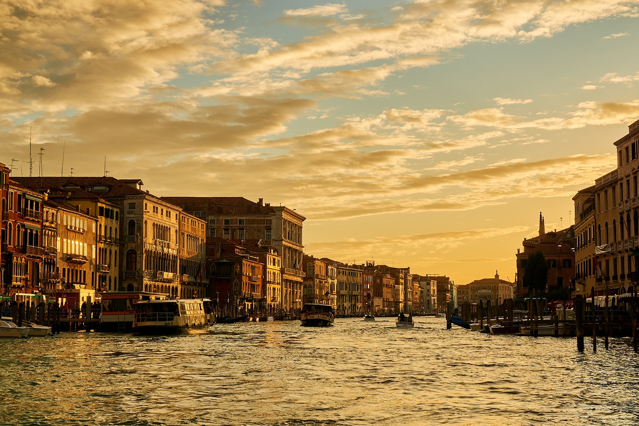 a canal filled with lots of water next to tall buildings, by Richard Carline, pexels, renaissance, setting sun. golden hour, venice biennale's golden lion, golden clouds, 6 4 0