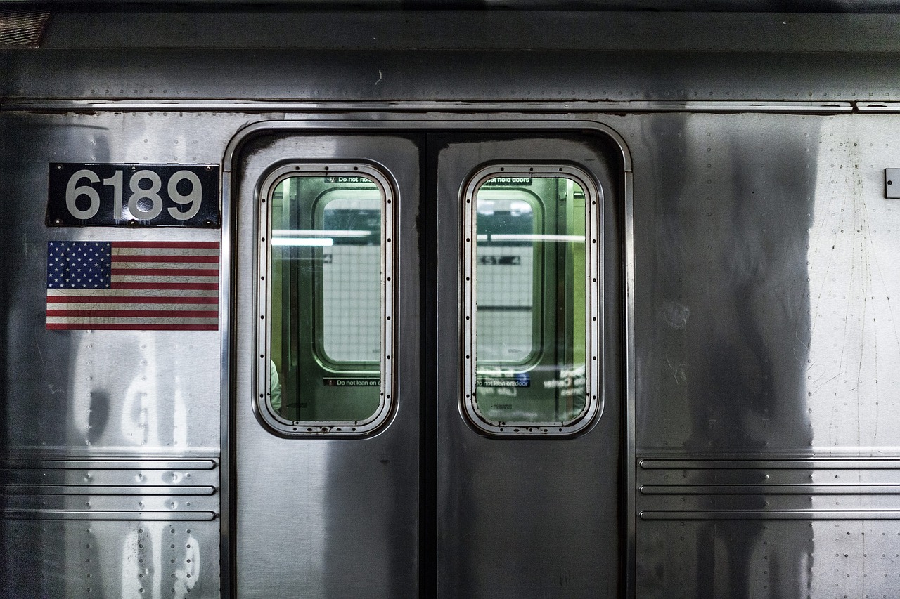 a close up of a train door with an american flag on it, by Joseph Pisani, unsplash, rows of windows lit internally, subways, new york city, stainless steal