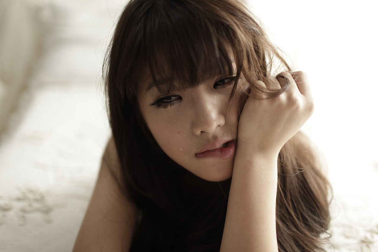 a beautiful young woman laying on top of a bed, a picture, tumblr, shin hanga, sad kawaii face, kim jung giu, lalisa manobal, close - up studio photo