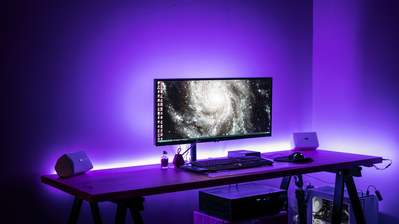 a computer monitor sitting on top of a wooden desk, by Bascove, light and space, violet lighting, led light strips, superwide shot, rgb wall light