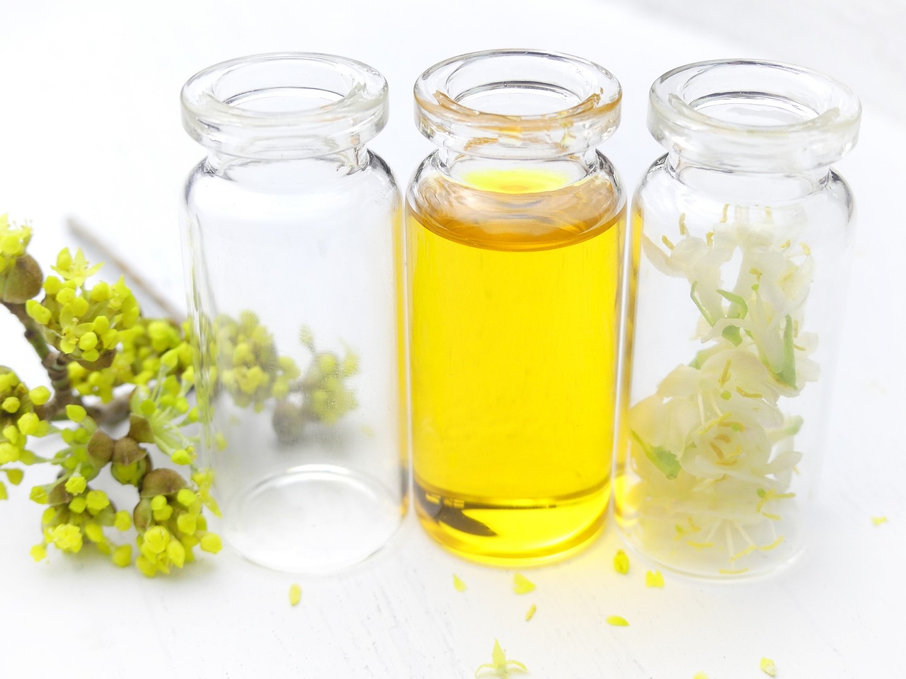 a close up of a bottle of oil next to a bunch of flowers, by Rhea Carmi, pexels, plants in scientific glassware, white and yellow scheme, jars, girls