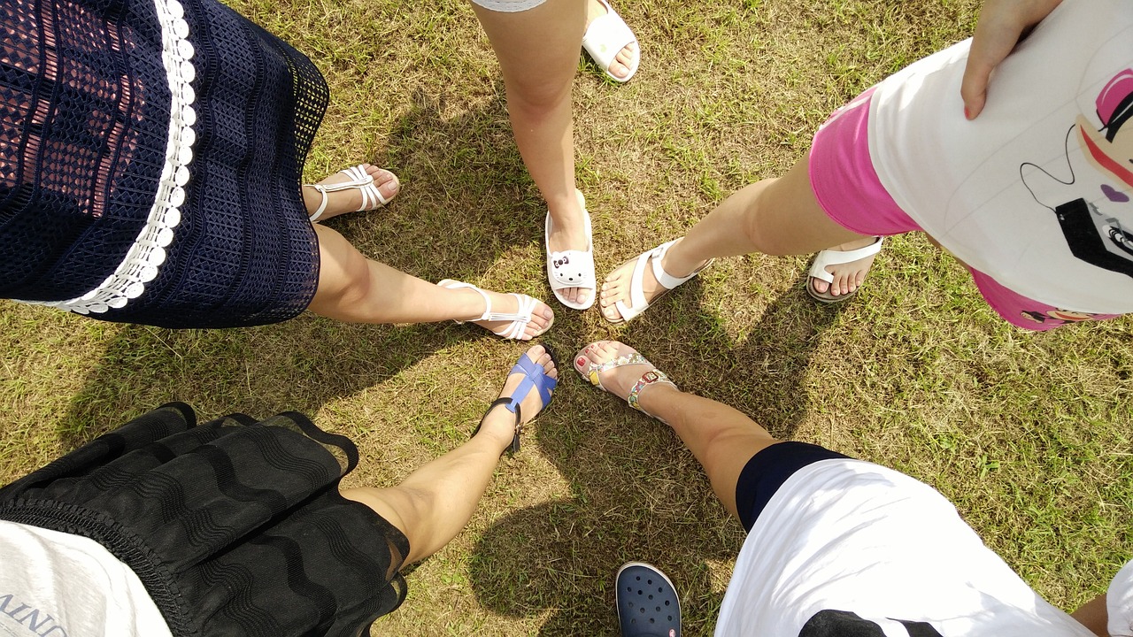 a group of people standing on top of a grass covered field, a picture, flickr, birkenstock sandals, girls, white shoes, human legs