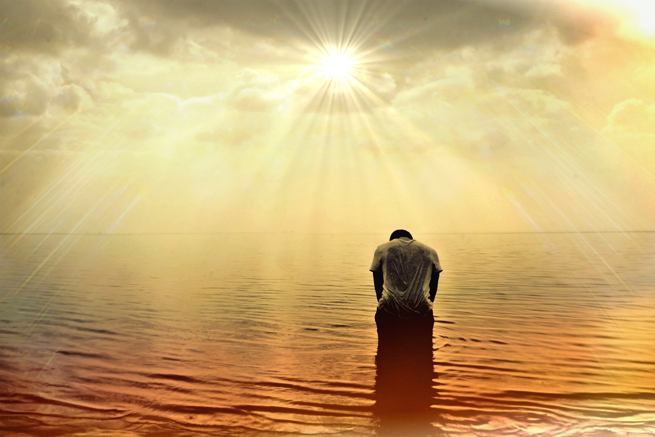 a man standing in the middle of a body of water, a picture, romanticism, praying at the sun, istockphoto, unhappy, kneeling