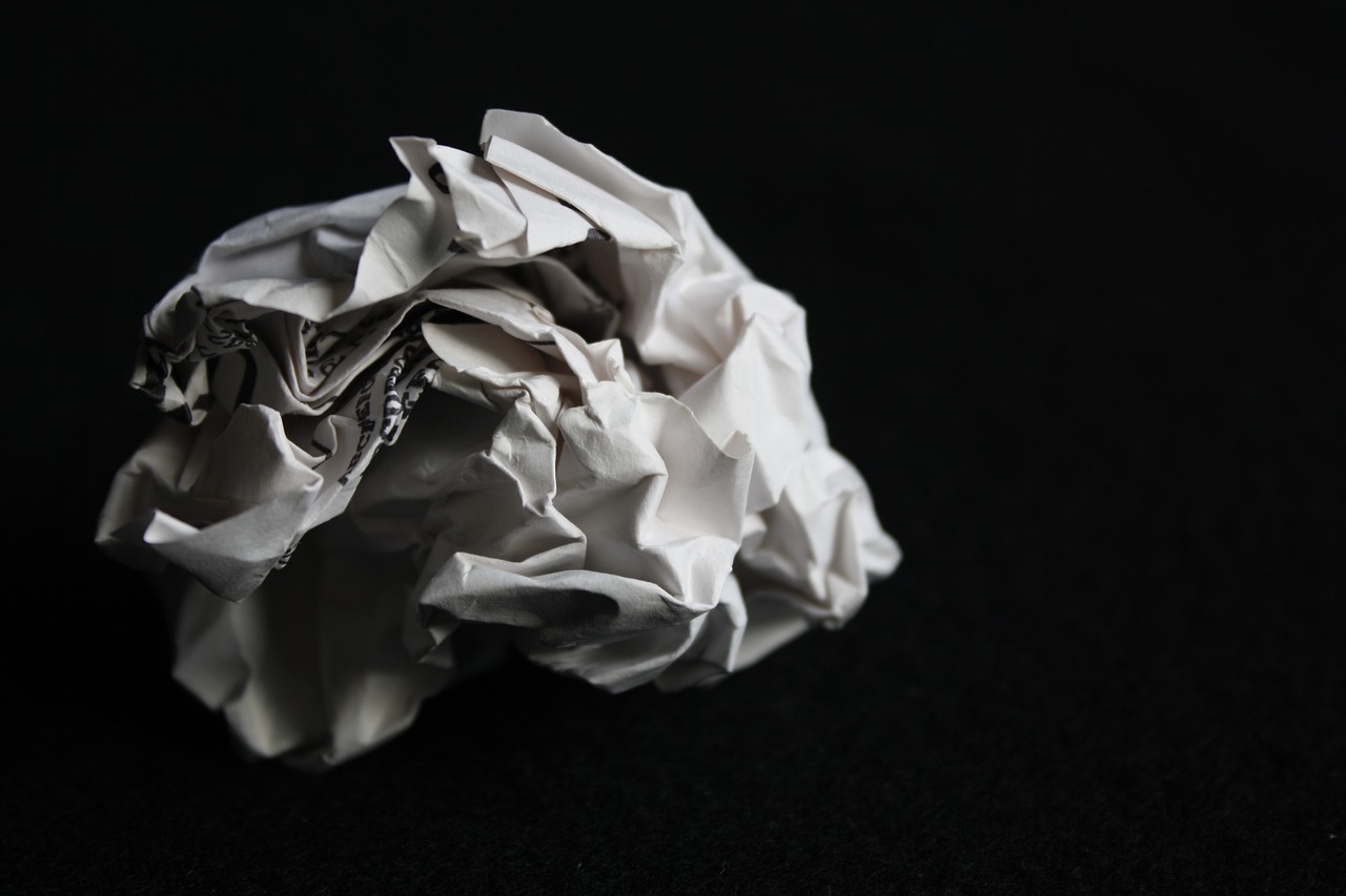 a crumpled piece of paper on a black surface, by Alexander Scott, 8 0 mm photo