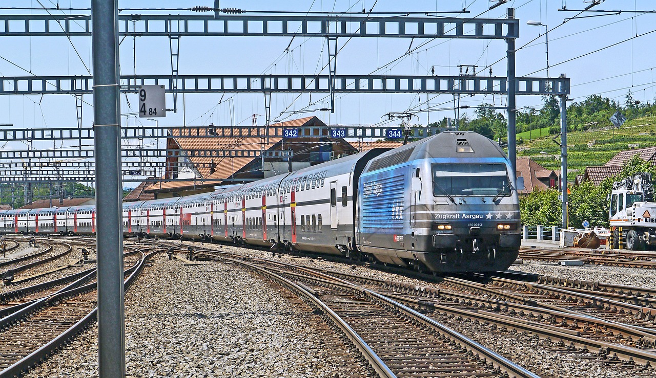 a large long train on a steel track, by Jens Søndergaard, traveling in france, charging through city, hsv, very sunny