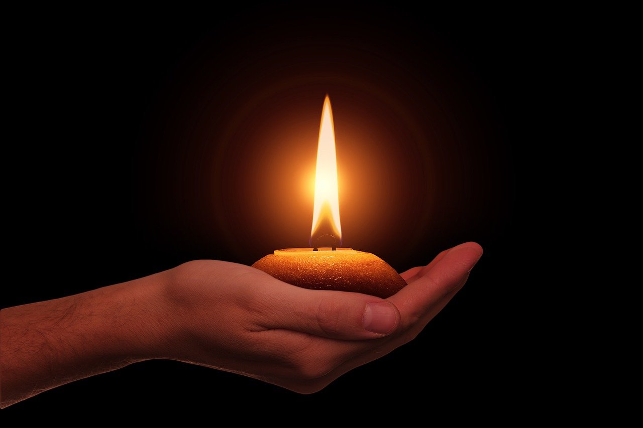 a person holding a lit candle in their hand, a digital rendering, by Juan O'Gorman, shutterstock, on black background, stock photo