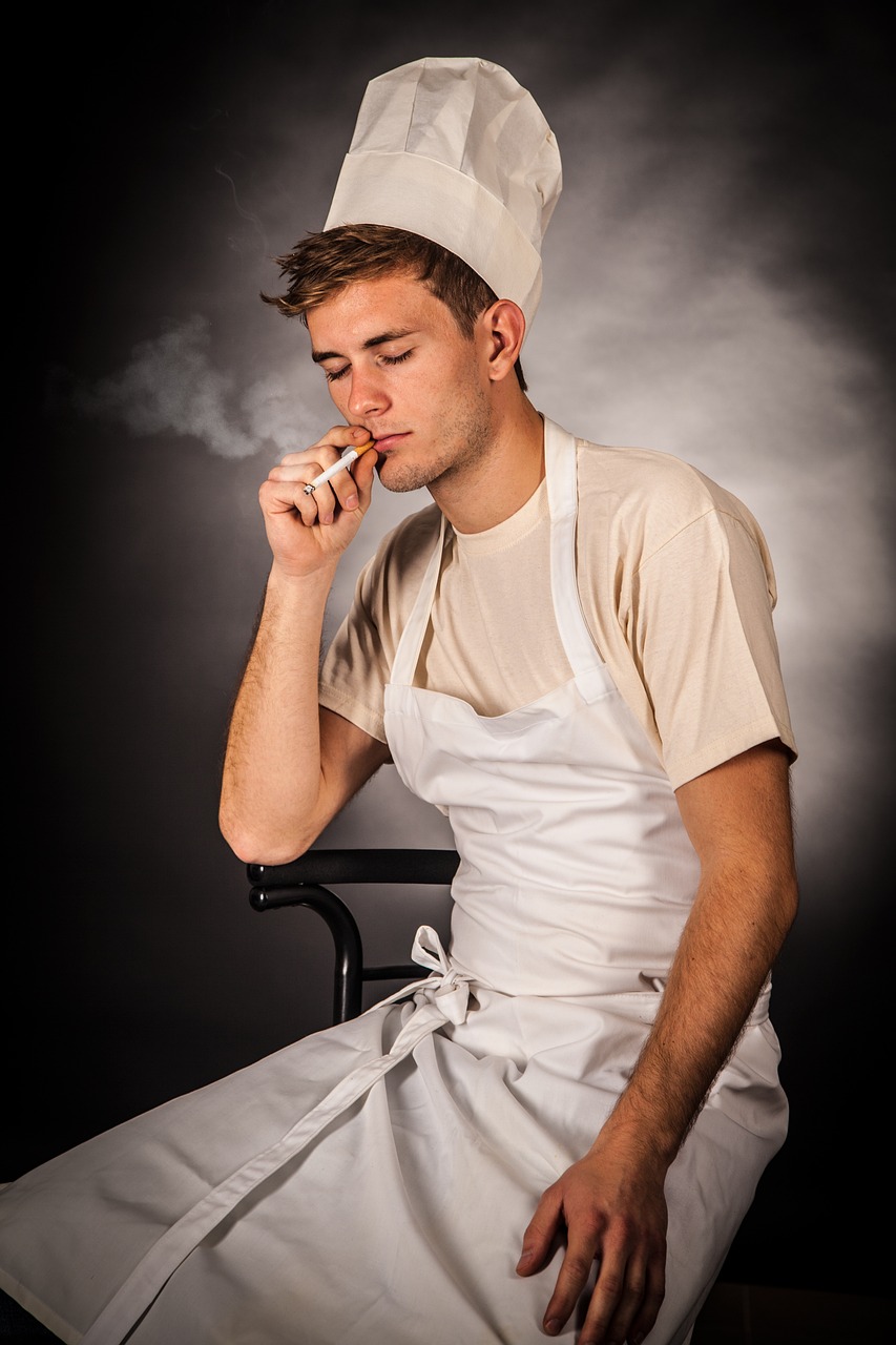 a man sitting on a chair smoking a cigarette, inspired by François Bocion, shutterstock, dressed as a pastry chef, white waist apron and undershirt, 21 years old, ryan dening