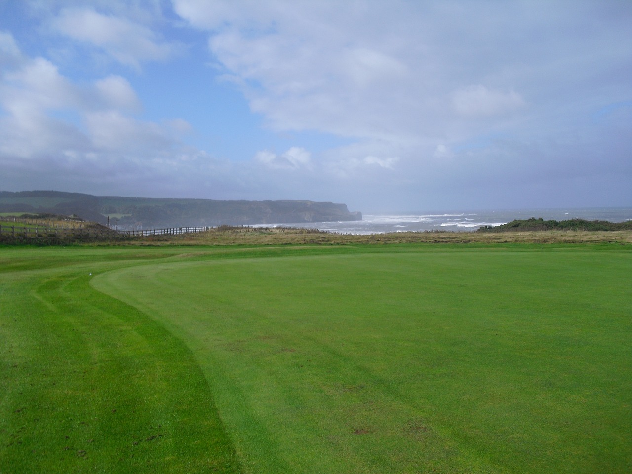 a green golf course with a view of the ocean, a picture, hurufiyya, cliffs, marsden, stubble, star
